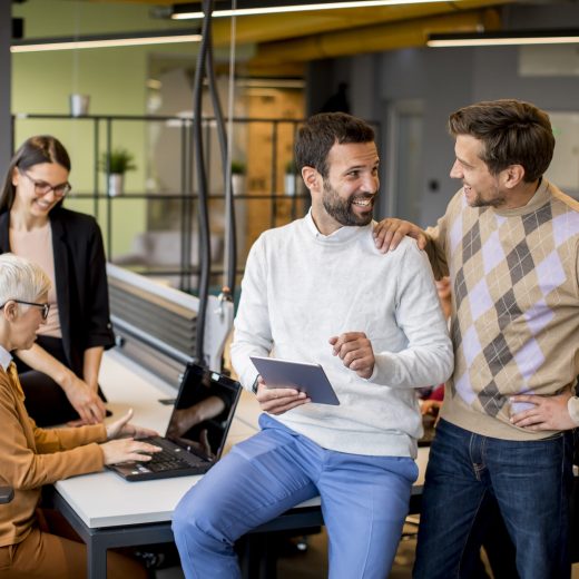 Group of business people working and communicating while standing in  the office together with colleagues sitting in the background